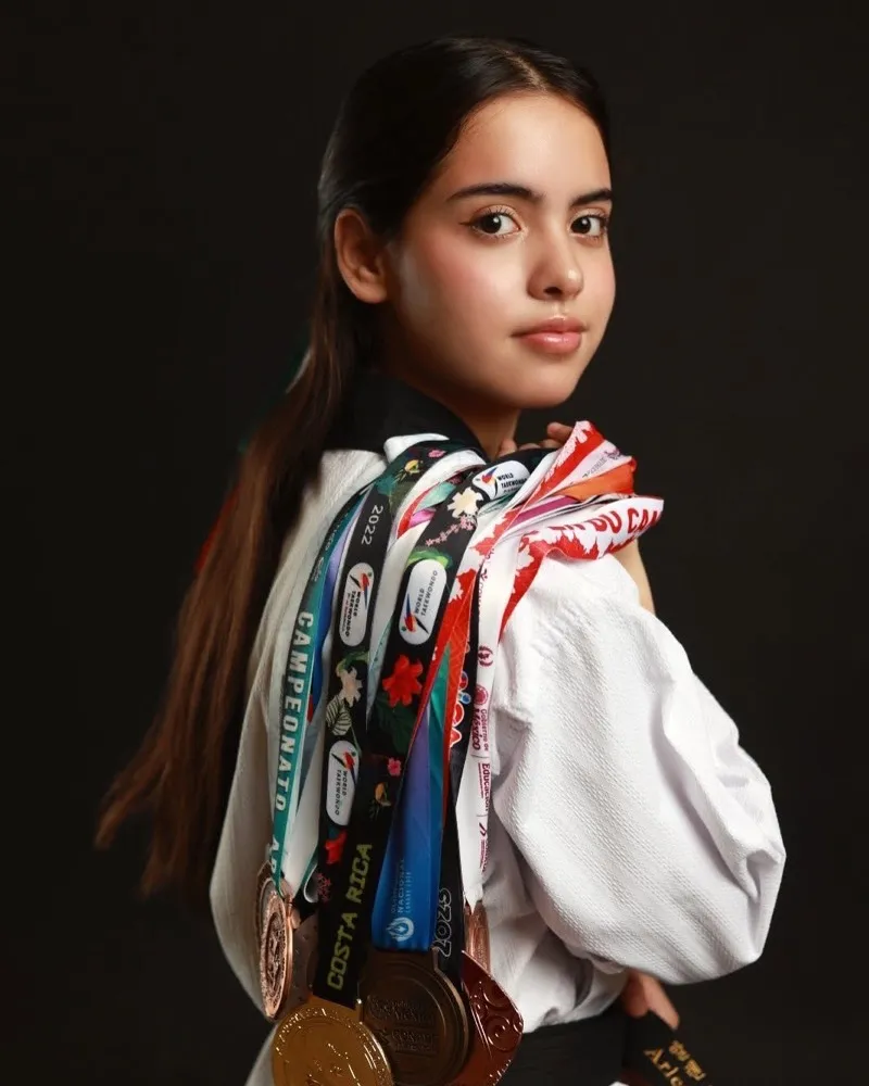 Atleta de taekwondo con sus medallas en el estudio