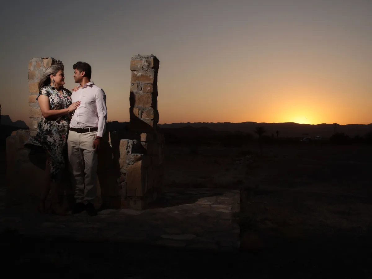 Pareja de novios al atardecer con el sol en el horizonte