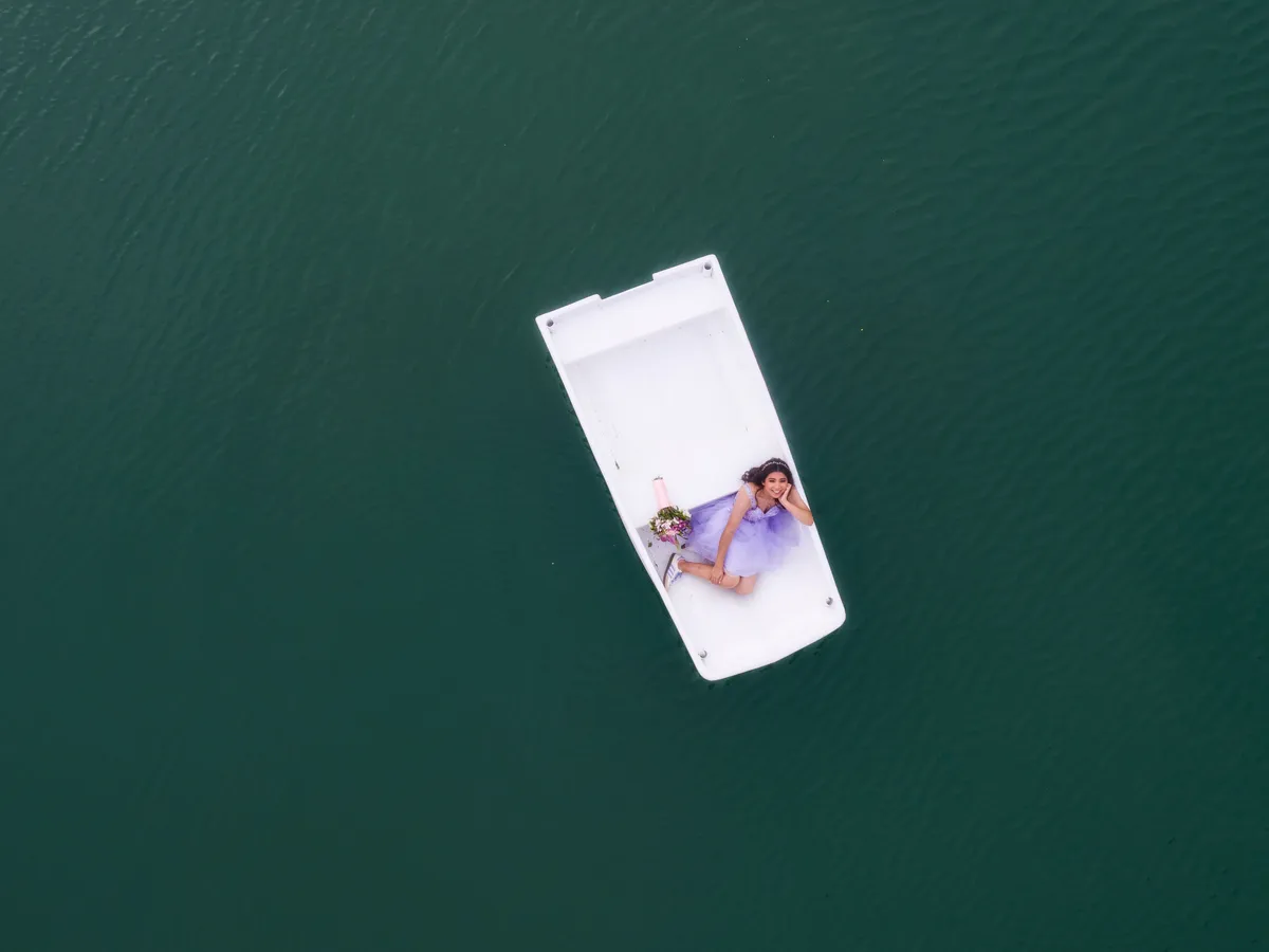 Vista aérea de una lancha blanca sobre un lago verde con una quinceañera a bordo