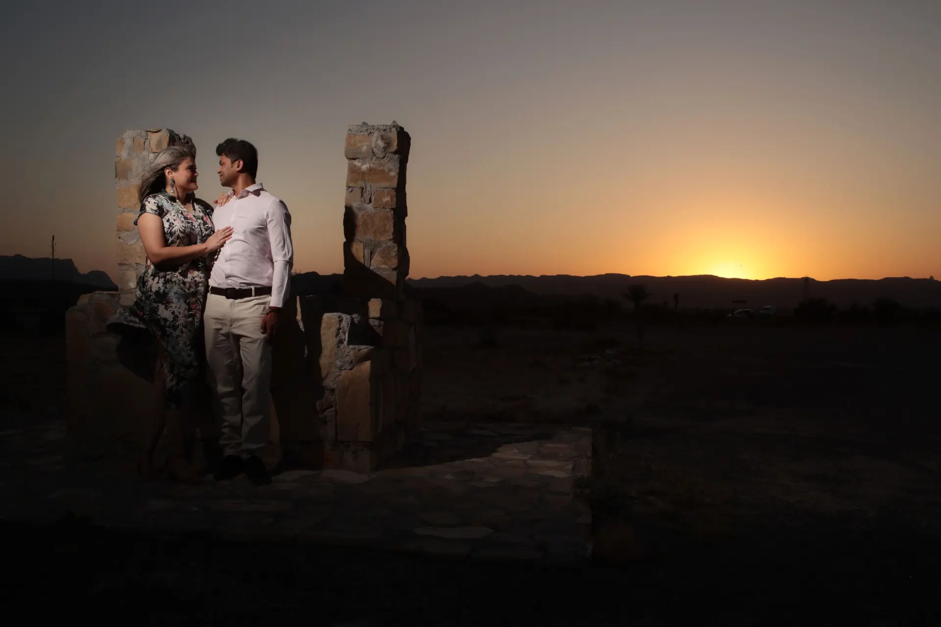 Pareja de novios al atardecer con el sol en el horizonte