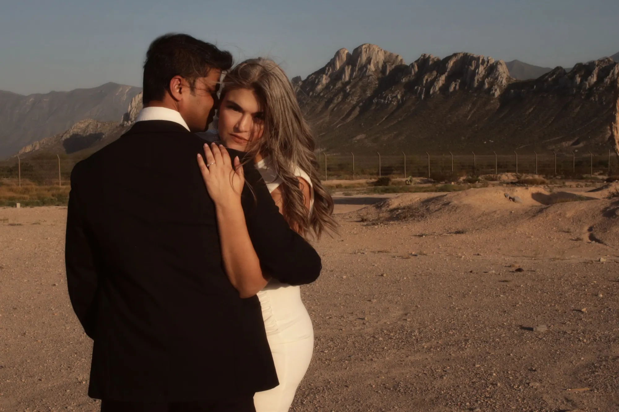 Pareja abrazada frente a una montaña al atardecer