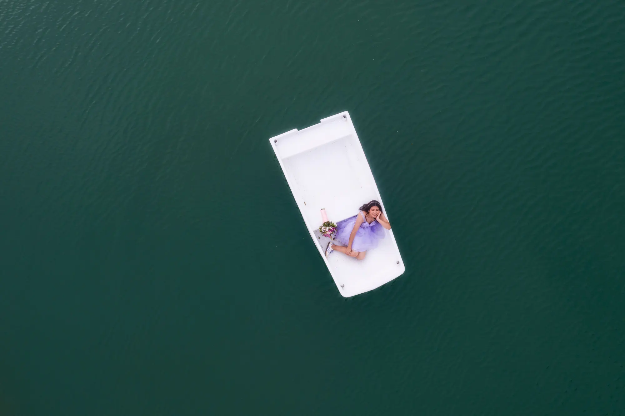 Vista aérea de una lancha blanca sobre un lago verde con una quinceañera a bordo