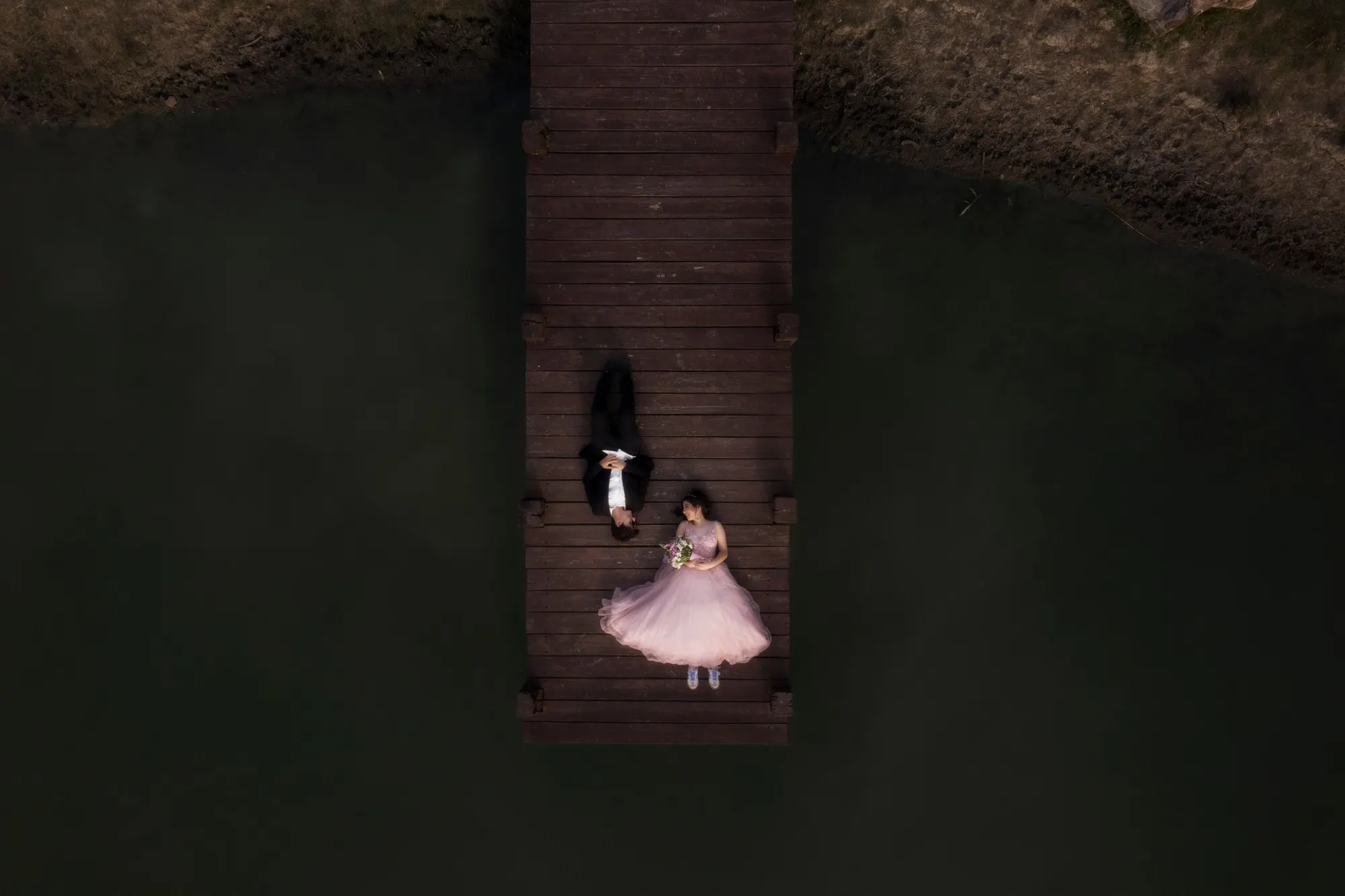 Vista aérea de una quinceañera en un muelle de madera sobre agua oscura