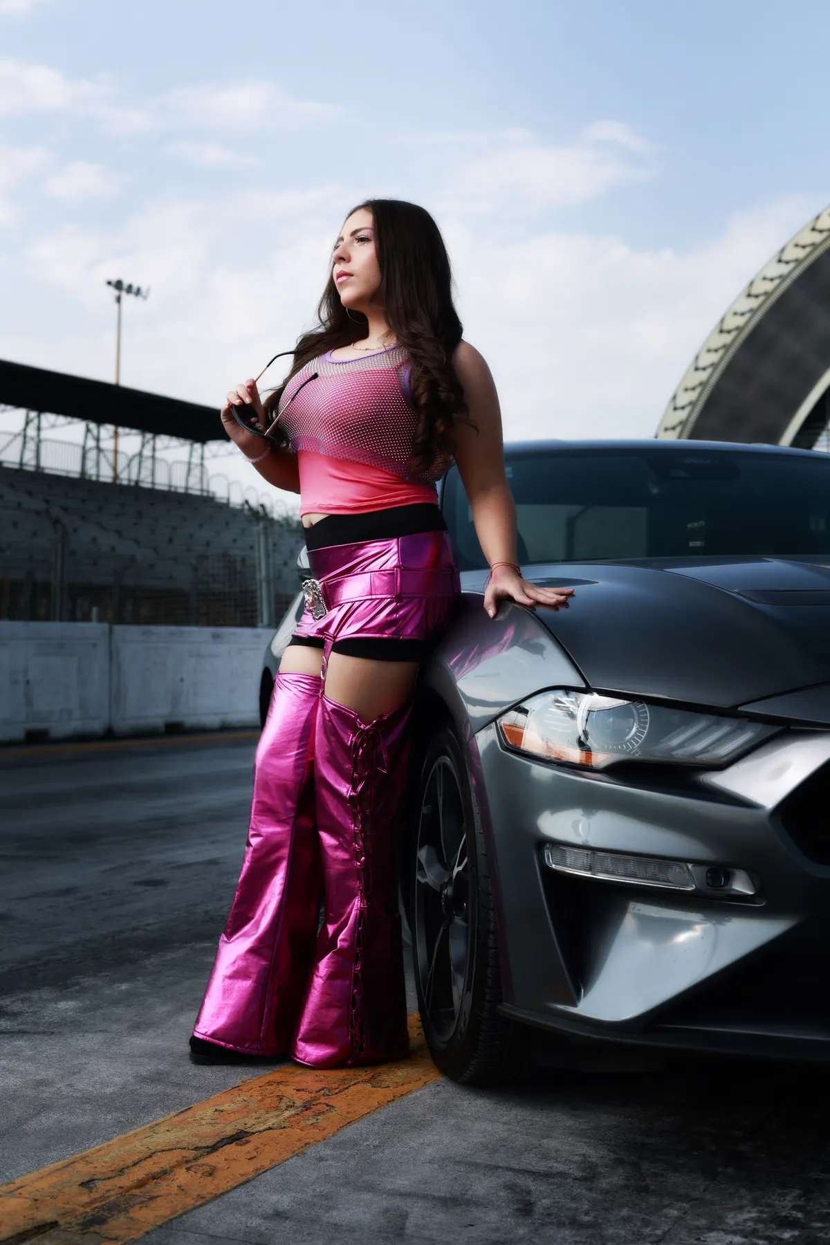 Retrato de XV años con ropa rosa recargada en un auto deportivo