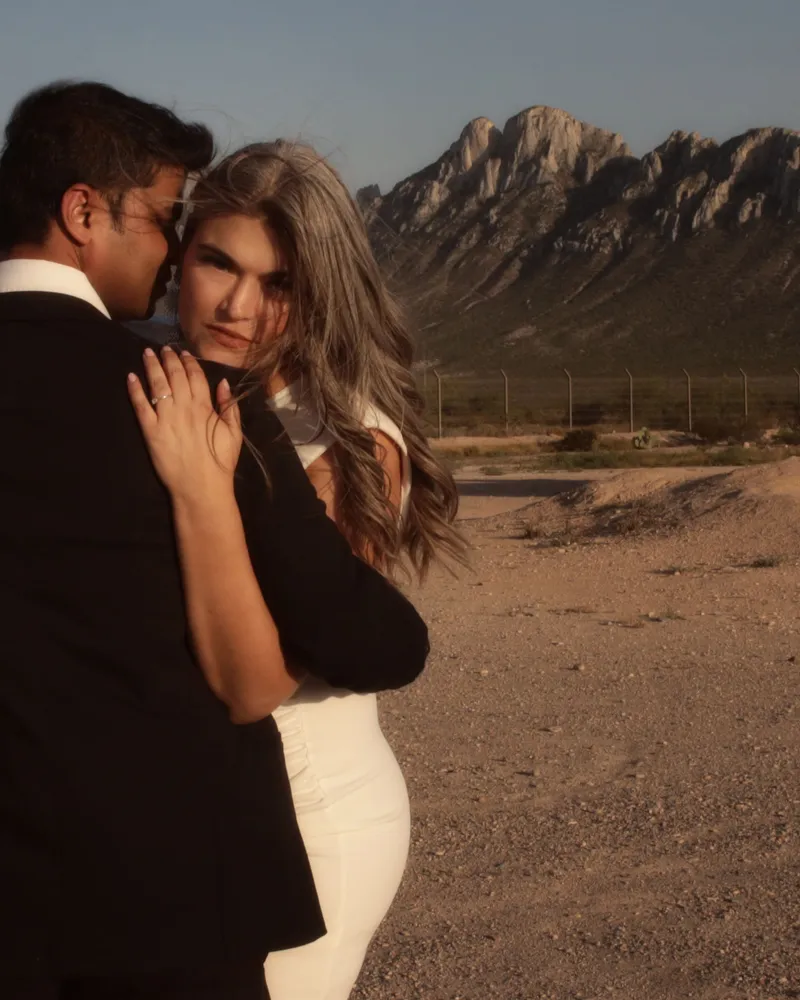 Pareja abrazada frente a una montaña al atardecer