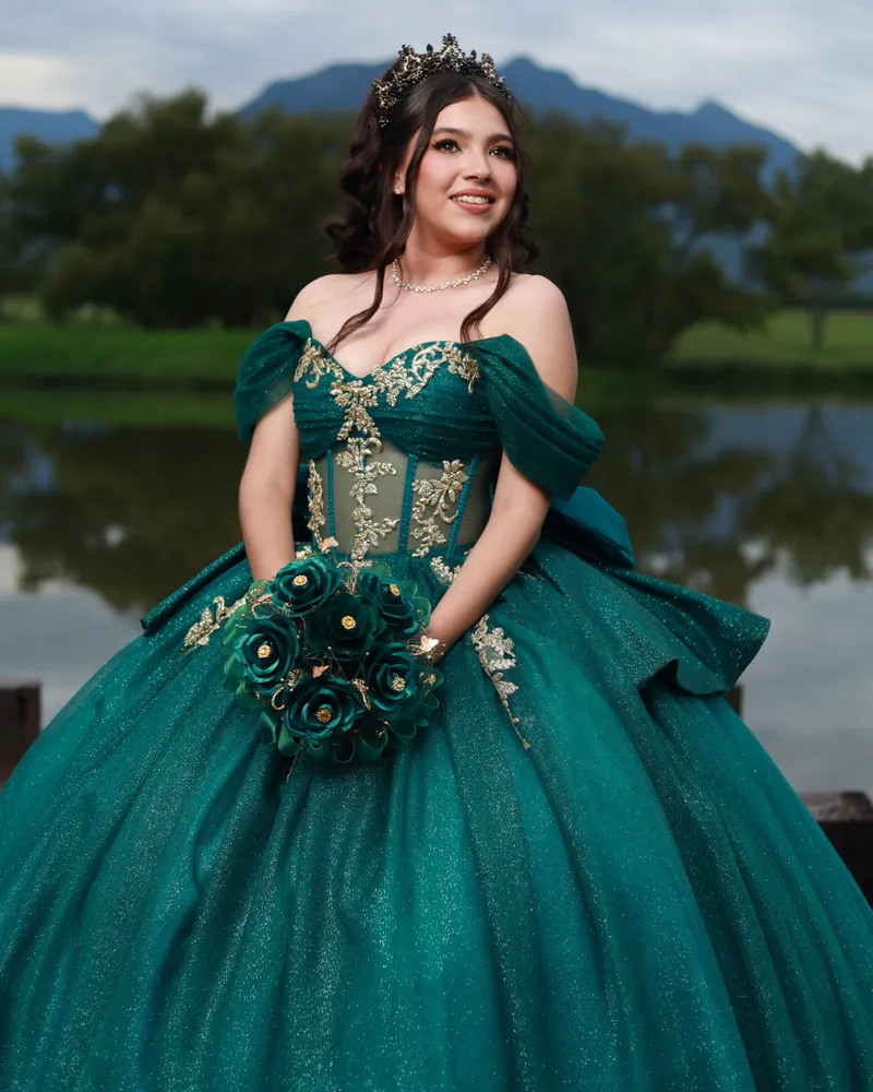 Quinceañera con vestido esmeralda junto a un lago